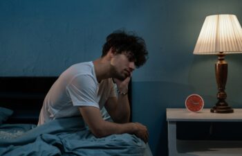 Depressed young arabic man sitting in bed cannot sleep from insomnia. Depression and sleep disorders concept